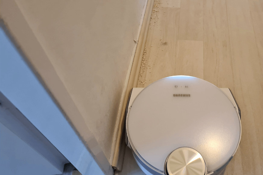 Der Samsung Jet Bot AI+ reinigt Schmutz entlang einer Leiste.